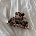 Dettaglio della molletta per capelli in acetato tartarugato con logo dorato su lino - Stampa Leopardata