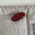 Detail shot of smooth dark red oval acetate hair clip on a beige linen fabric background - Oval Hair Clip