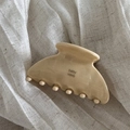 Detailed close-up of a glossy cream acetate hair claw clip on soft textured linen fabric - Cheese Color