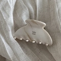 Detail of cream marble cellulose acetate hair claw clip on soft linen fabric texture - Creamy White