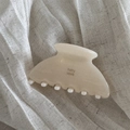 Close-up of cream acetate hair claw clip with smooth jelly texture on linen fabric - Ivory White