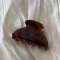 Detailed view of brown tortoiseshell hair claw with golden baby vovo logo on linen - Caramel Color