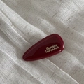 Macro di un fermaglio per capelli rosso scuro lucido con testo Barrette LaFrance dorato - Goccia - Rosso Vino