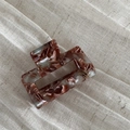Close-up of tortoise shell pattern acetate hair claw clip on soft fabric background - Green & Coffee