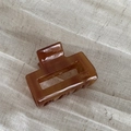 Detailed macro view of an amber brown acetate hair claw with FRANCE Handmade engraving - Light Coffee