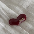 Dettaglio di un fermaglio per capelli in resina bordeaux con scritte dorate su lino - Forma di Cuore - Rosso Vino