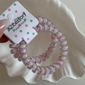 Close-up of pink floral spiral telephone wire hair ties on a white accessory card - Light Pink Thick