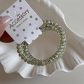 Detail of light green polka dot spiral hair ties set in a white shell-shaped tray - Grass Green Thin