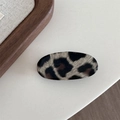 Nahaufnahme der Haarspange mit Leopardenmuster und glatter Oberfläche auf Holzuntergrund - Beige Leopard-Oval
