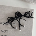 Dettaglio del fermaglio nero con fiocco di perline e perle bianche su sfondo di lino - Clip Fiocco con Perline - Nero