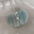 Vista macro dettagliata del fermaglio orchidea azzurro con perla su piatto di ceramica - Blu