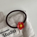 Elastisches Haargummi mit einer hellen rot-gelben Blume auf einer beigen Stofftasche - Haargummi / Rot