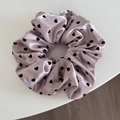 Dettaglio di scrunchie in raso rosa con cuori neri e trama setosa lucida - Rosa