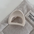 Macro detail of a cream-colored arched hair claw clip with glossy finish and wavy teeth - Chubby Triangle-White