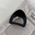 Detail view of small triangle hair claw clip in glossy black finish on canvas background - Chubby Triangle-Black