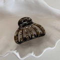 Detail view of acetate shell hair claw with marble texture on a ceramic tray - Floral Coffee