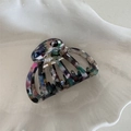 Detailed close-up of a marble-patterned acetate hair claw clip on a ceramic tray - Iridescent Mixed Blue