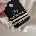 Three acetate hair clips in tortoise shell and cream patterns on a black display card - Milk Coffee