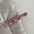 Detailed close-up of pink marbled acetate hair clip clipped on a linen texture background - Pink and Green