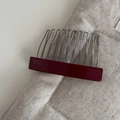 Macro detail of wine red acetate hair comb with silver metal wavy teeth and gold logo - Burgundy
