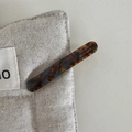 Close-up of tortoise shell pattern barrette on linen pouch with golden engraving - Blue Brown