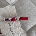 Détail d'une barrette en acétate à motif marbré avec épissage rouge et lettrage doré - Rose