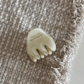 Detalle de una pinza para el pelo de acetato beige con letras doradas sobre tela crema - Blanco Roto