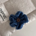 Detailansicht der handgemachten blauen Häkelblumen-Haarklammer mit weicher Wollstruktur - Blau