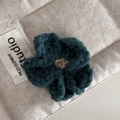 Makroaufnahme einer handgehäkelten Blume in Pfauenblau mit klarer Wolltextur-Detail - Grün