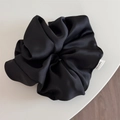 Detail of premium black satin oversized scrunchie featuring a handmade woven label - Black