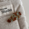 Detail view of acetate teardrop hair clip with green marble texture and handmade engraving - Green & Coffee