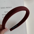 Detalle de diadema de tela rojo oscuro con etiqueta hecha a mano sobre fondo de libro - Estilo Estrecho / Burdeos