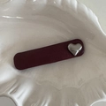 Detail view of burgundy leather hair clip with a silver metallic heart on a shell tray - Wine Red Rectangular