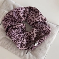 Detail van paarse luipaardprint scrunchie met leren strik en zilveren metalen hanger logo - Roze Luipaard Scrunchie
