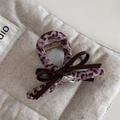 Detailweergave van haarclip met roze luipaardprint en leren strik op linnen ondergrond - Roze Luipaard Haarklem