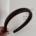Detail of a thick dark brown leather headband with a handmade label on a book - Dark Coffee (Soft Leather Headband)