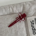 Detailed view of a vintage burgundy polka dot bow hair clip on a rustic linen background - Red