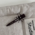 Detail view of a dark coffee bow hair clip with white polka dots on textured fabric - Dark Coffee