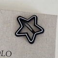Dettaglio del fermaglio per capelli a stella nero e bianco con texture opaca su lino - Base Nera Linea Bianca - Stella