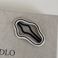 Dettaglio della clip BB a forma di onda con intaglio in metallo nero e cuciture a contrasto - Base Bianca Linea Nera - Nuvola