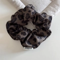 Primo piano di scrunchie leopardato con texture satinata liscia e dettagli plissettati - Scrunchie Leopardato / Marrone