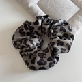 Dettaglio di elastico per capelli in seta leopardata con etichetta su lino beige neutro - Scrunchie Leopardato / Cachi