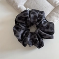 Dettaglio dell'elastico scrunchie in raso maculato grigio con pieghe e etichetta - Scrunchie Leopardato / Grigio