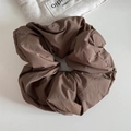 Detailed macro view of the wrinkled texture on a coffee brown fabric scrunchie accessory - Coffee