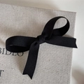 Vista detallada de un lazo de tela negra para el pelo sobre una caja de lona elegante - Nudo Minimalista Color Sólido-Negro