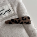 Dettaglio macro di un fermaglio per capelli leopardato su sfondo in lino testurizzato - Stile Triangolare in Tessuto Leopardato