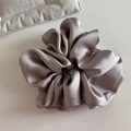Detailed view of large mauve satin scrunchie with soft fabric pleats and elegant silk sheen - Beige Apricot