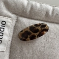 Macro shot of oval leopard print acetate hair clip on soft quilted fabric - Yellow Base Fur Leopard