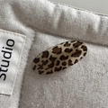 Dettaglio macro di un fermaglio per capelli ovale leopardato con finitura lucida su lino - Leopardo Beige