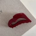 Close-up of dark red acetate hair claw with Barrette La France gold stamp on linen - Red